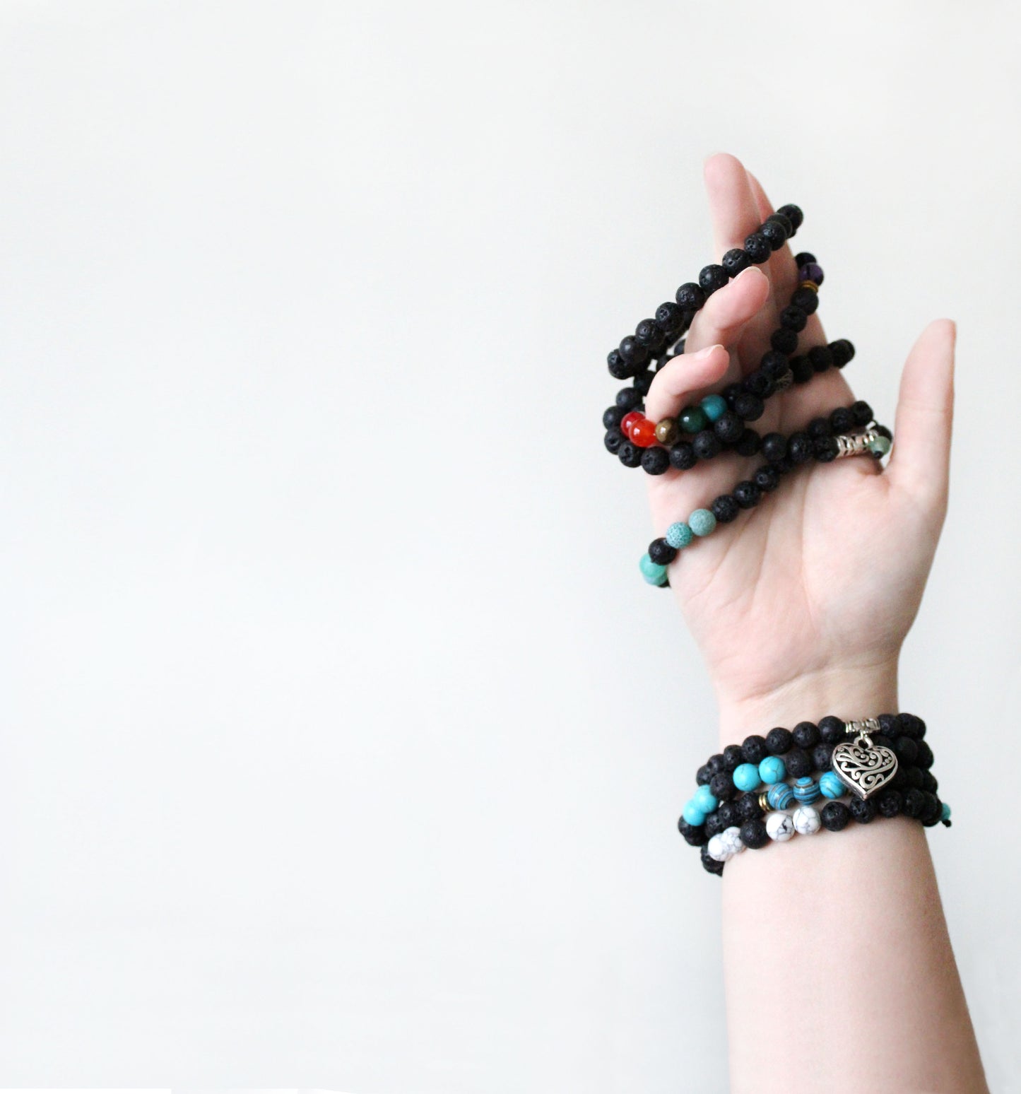 Hand wearing multiple Aromatherapy beaded bracelets on a white background