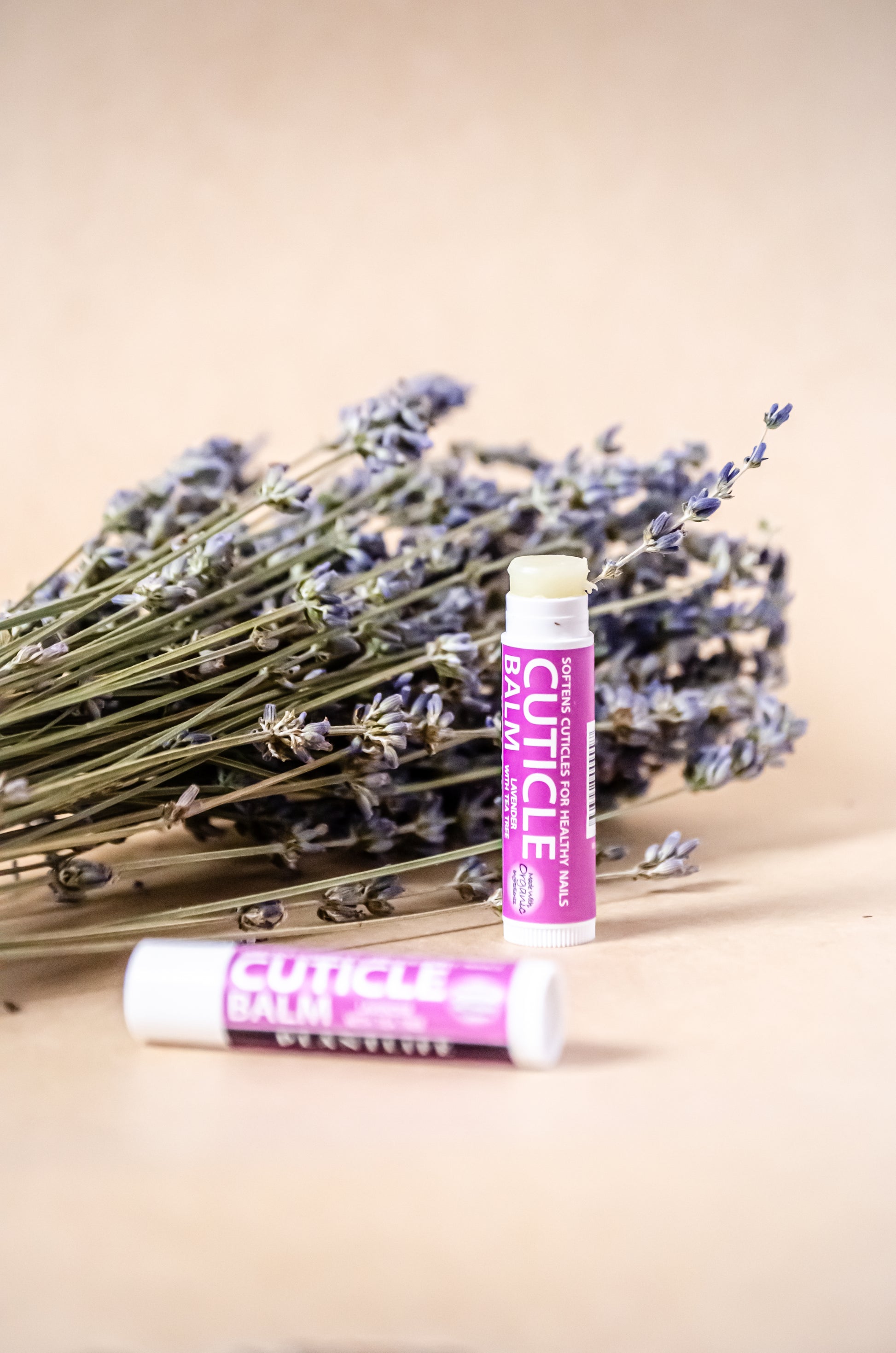 Plantlife Lavender Tea Tree Cuticle Balm with dried lavender bundle on beige background, promoting natural nail care.