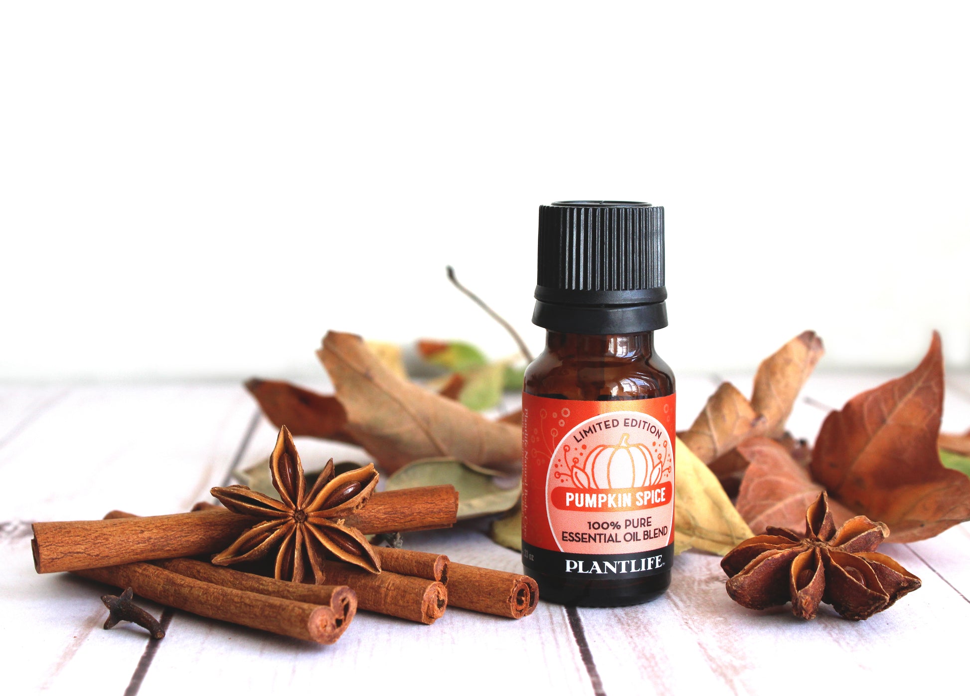 Bottle of Plantlife Pumpkin Spice essential oil with cinnamon sticks and star anise on a white background