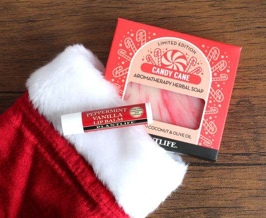 Candy cane-themed soap, lip balm, and soap bar on a wooden surface with Santa hat.