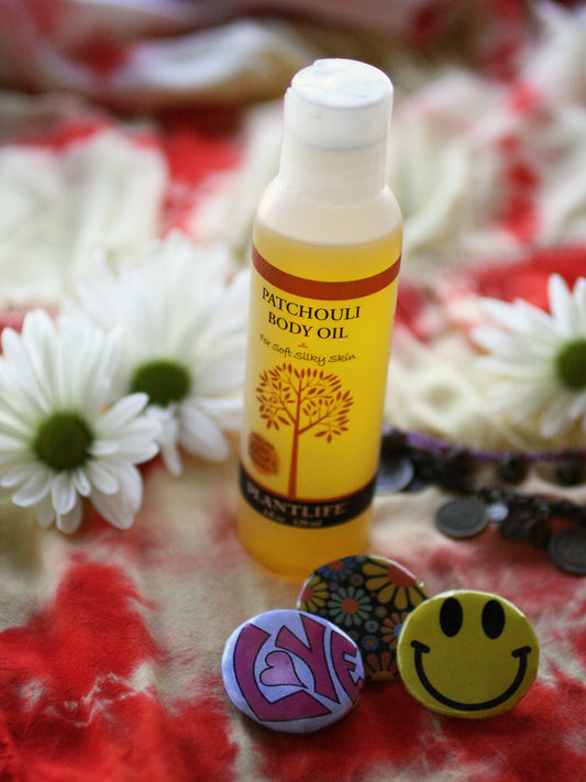 Patchouli body oil bottle with decorative buttons and flowers on a patterned fabric background