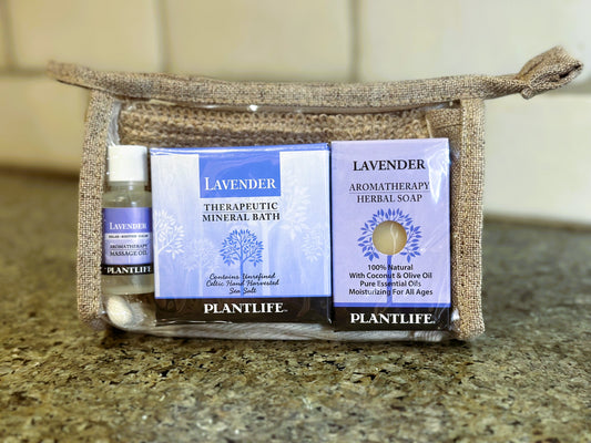 Plantlife Lavender gift set in a woven pouch with therapeutic mineral bath, aromatherapy herbal soap, and massage oil on a countertop