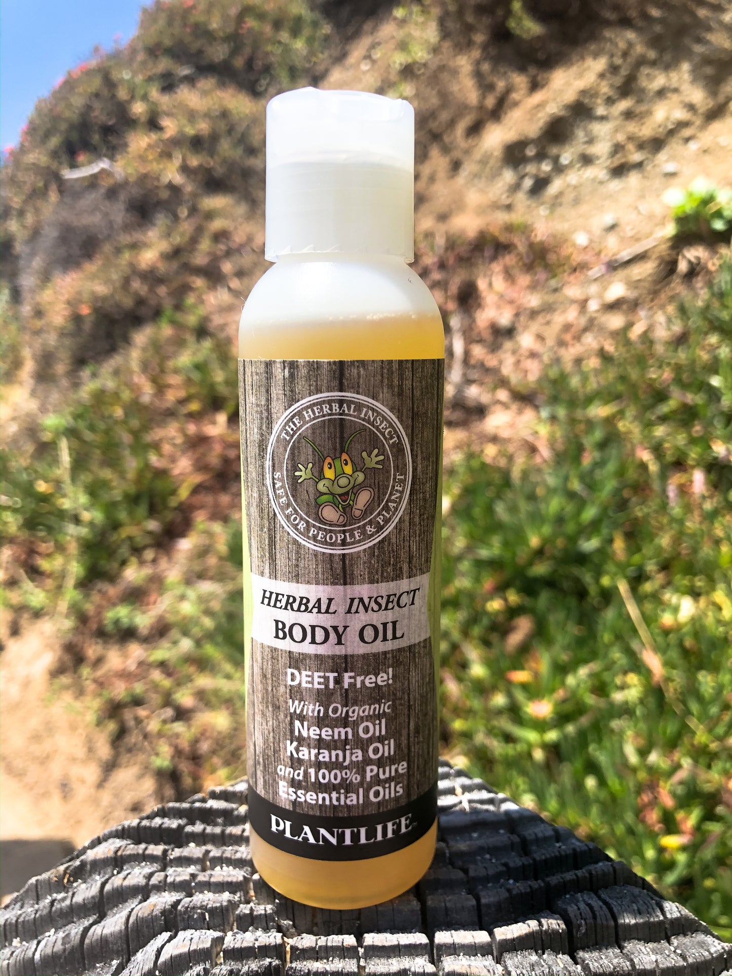 Bottle of Herbal Insect Body Oil by Plantlife on a textured surface with a natural background