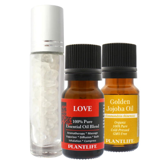 Clear glass roller bottle with white gemstone chips, alongside Plantlife Love Essential Oil Blend and Golden Jojoba Oil in amber glass bottles with black caps.