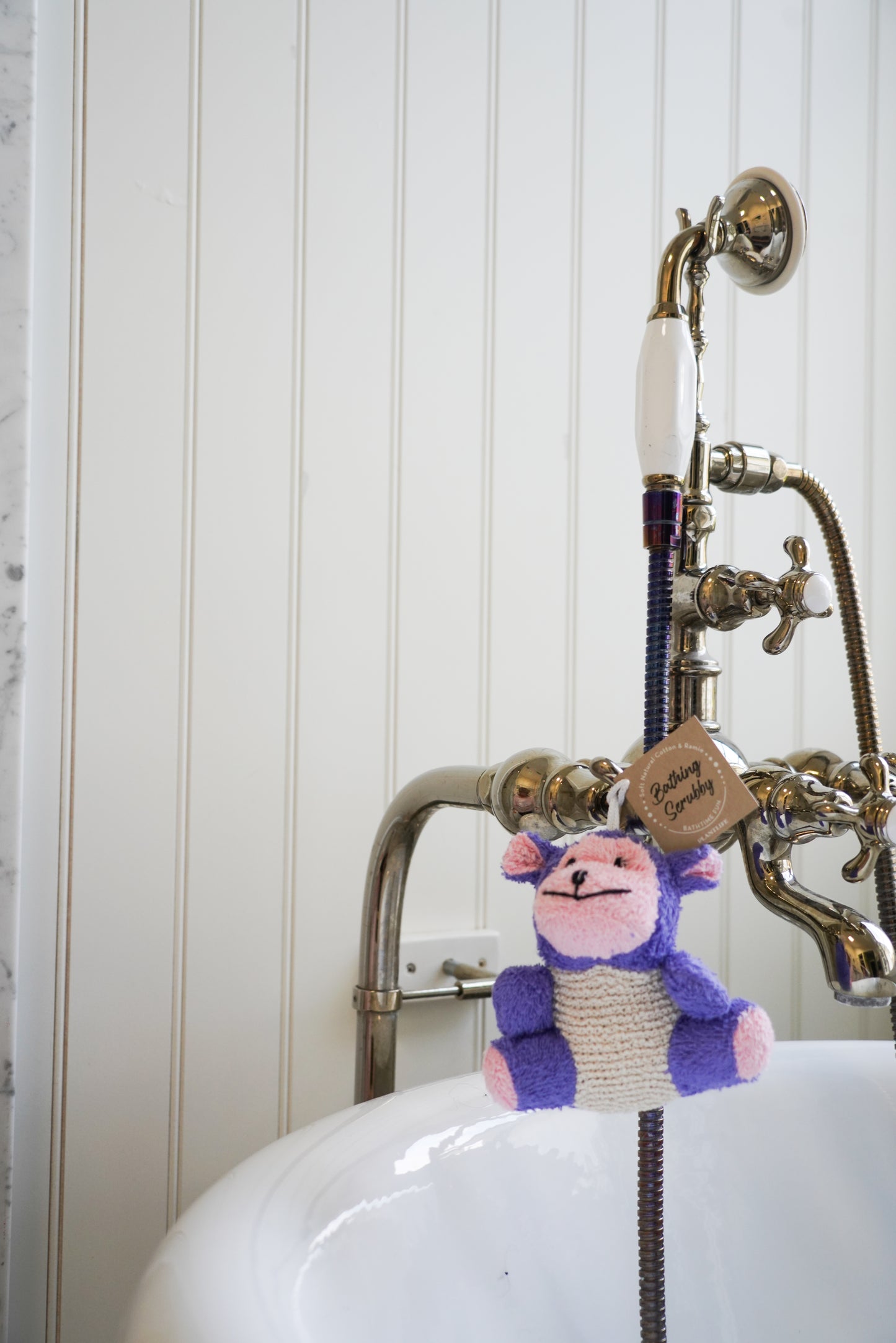 Knitted monkey toy hanging from a faucet in a bathroom setting