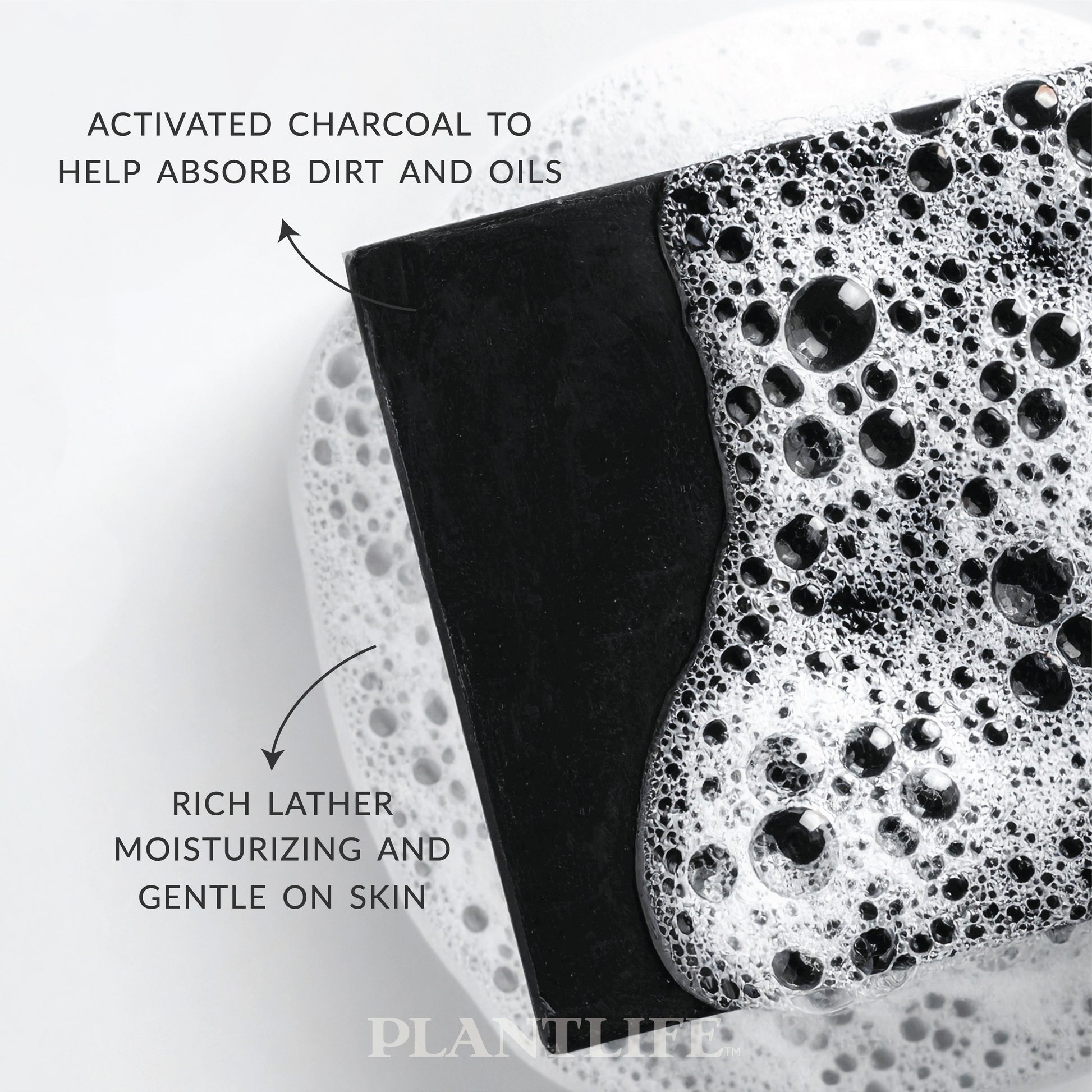 Close-up of a black Plantlife soap bar resting in foamy water. Text on the image highlights “Activated charcoal to help absorb dirt and oils” and “Rich lather, moisturizing and gentle on skin.”