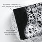 Close-up of a black Plantlife soap bar resting in foamy water. Text on the image highlights “Activated charcoal to help absorb dirt and oils” and “Rich lather, moisturizing and gentle on skin.”