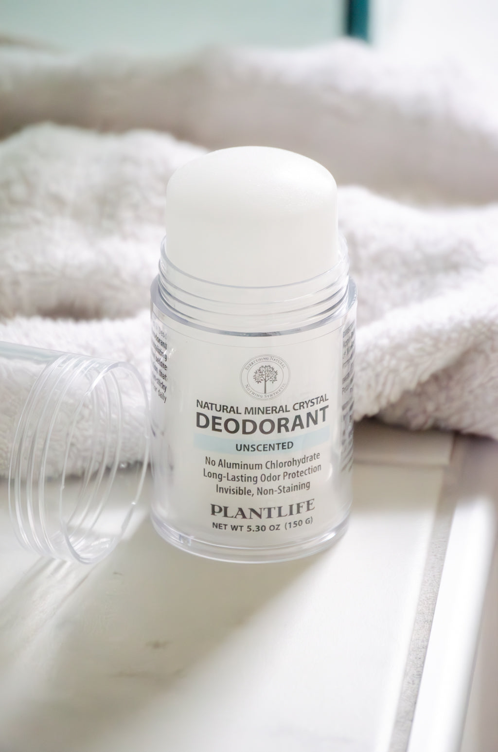 Plantlife natural mineral crystal deodorant on a white surface with a towel in the background