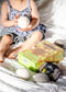 Child holding dryer balls with packaging on a bed