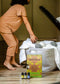 Person sorting laundry with a box of dryer balls and Plantlife products on a wooden floor.