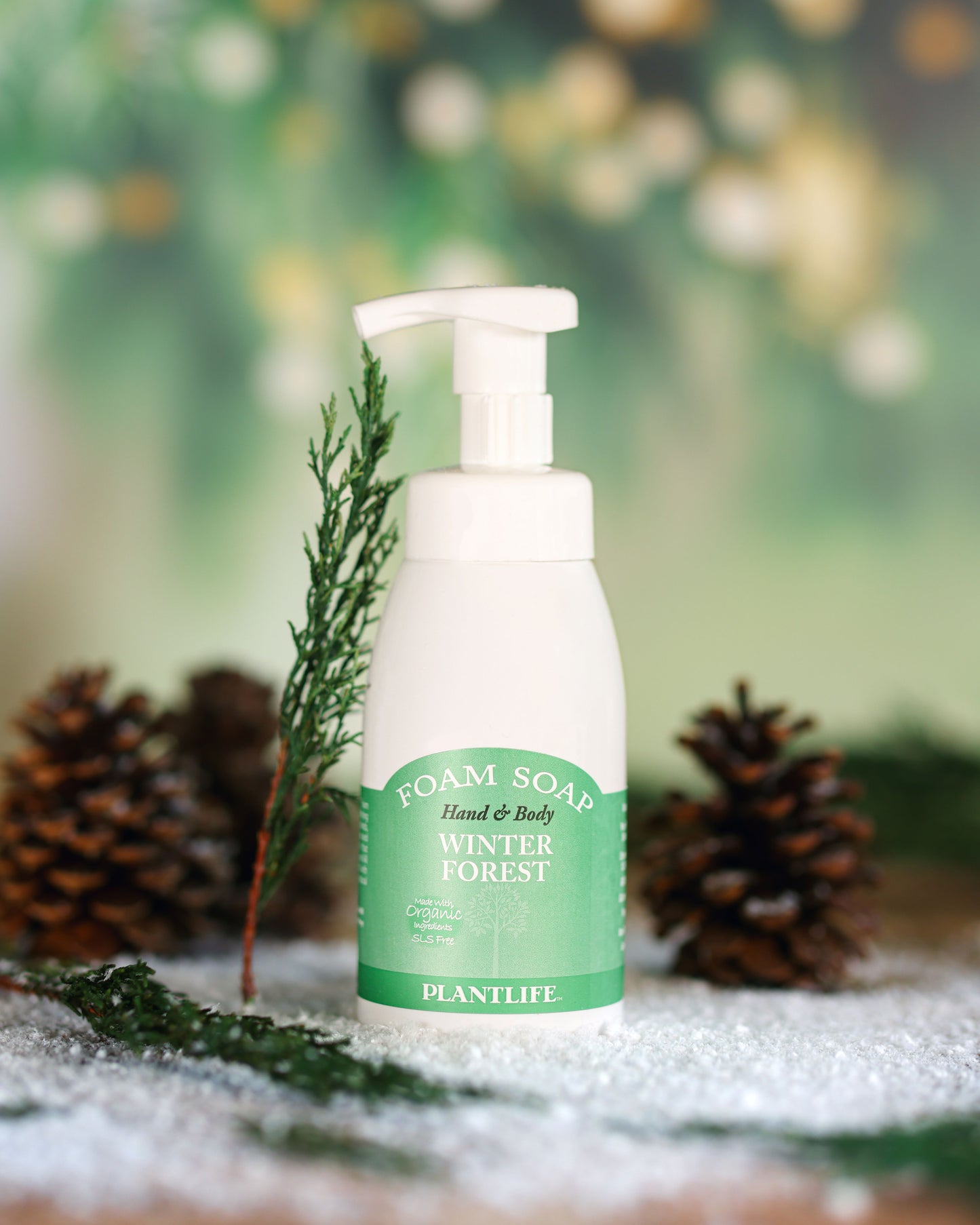 Foam soap bottle labeled 'Winter Forest' by Plantlife with decorative elements on a blurred natural background.