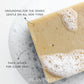 Close-up of a tan Plantlife soap bar resting in bubbly water. Text on the image highlights “Grounding for the senses, gentle on all skin types” and “Thick lather for clean skin.”