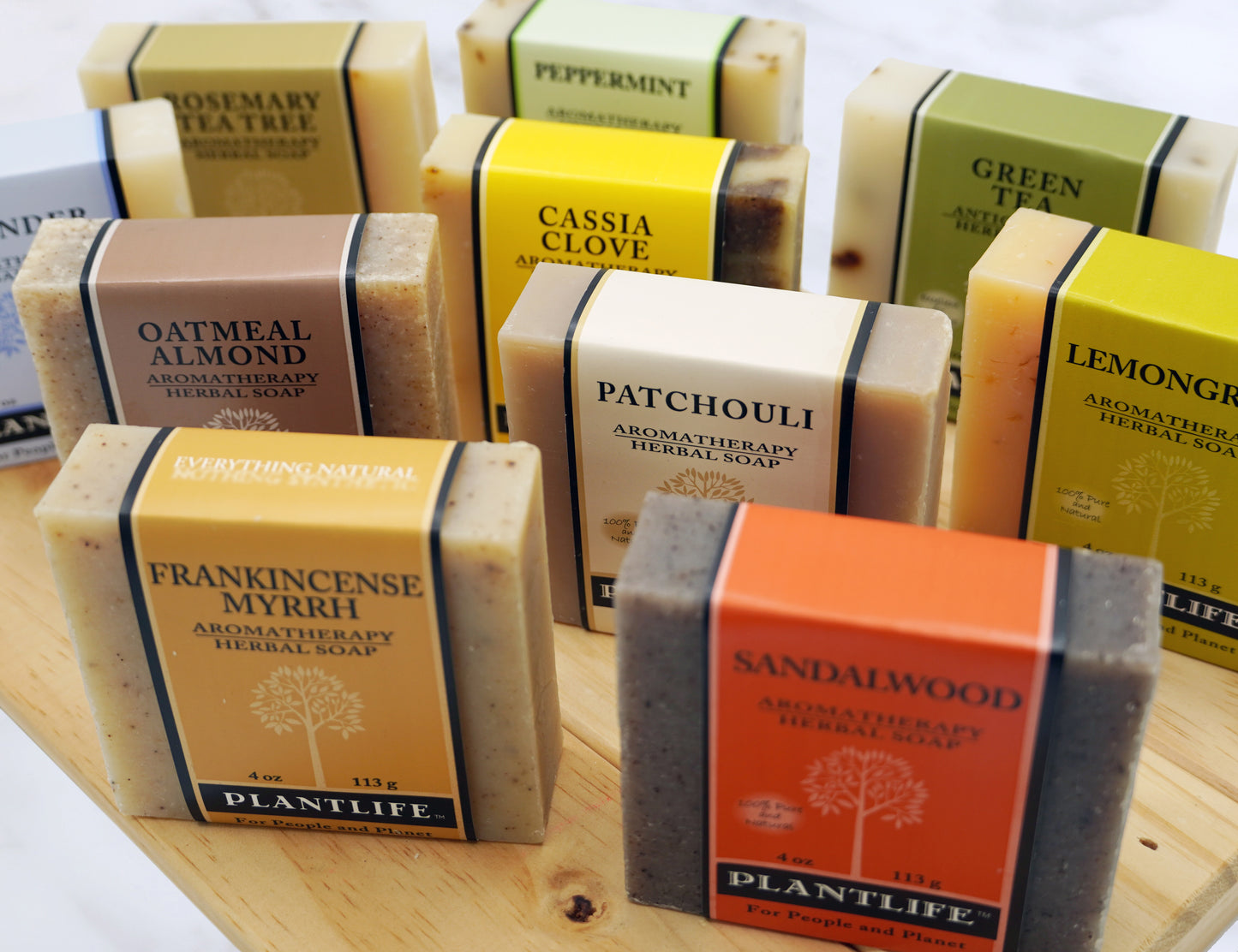 Assorted PLANTLIFE aromatherapy herbal soaps with natural ingredients on a wooden surface