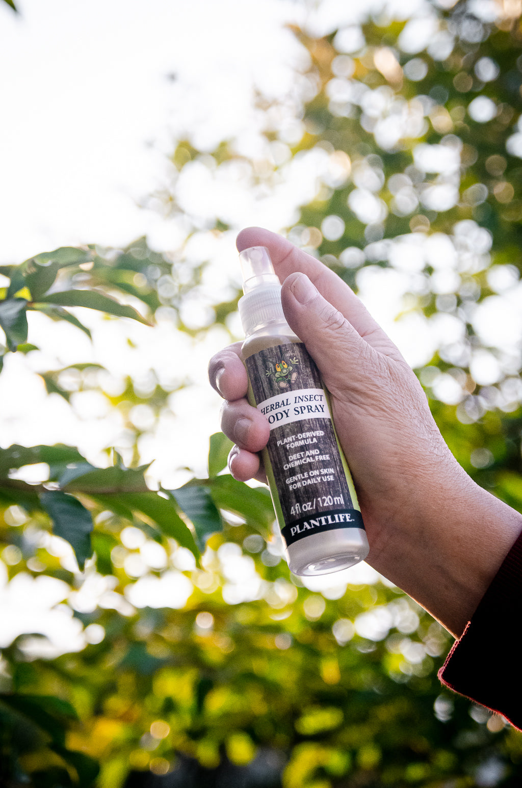 Plantlife Herbal Insect Body Spray 4 fl oz held outdoors with greenery, featuring a DEET-free plant-derived formula for daily use