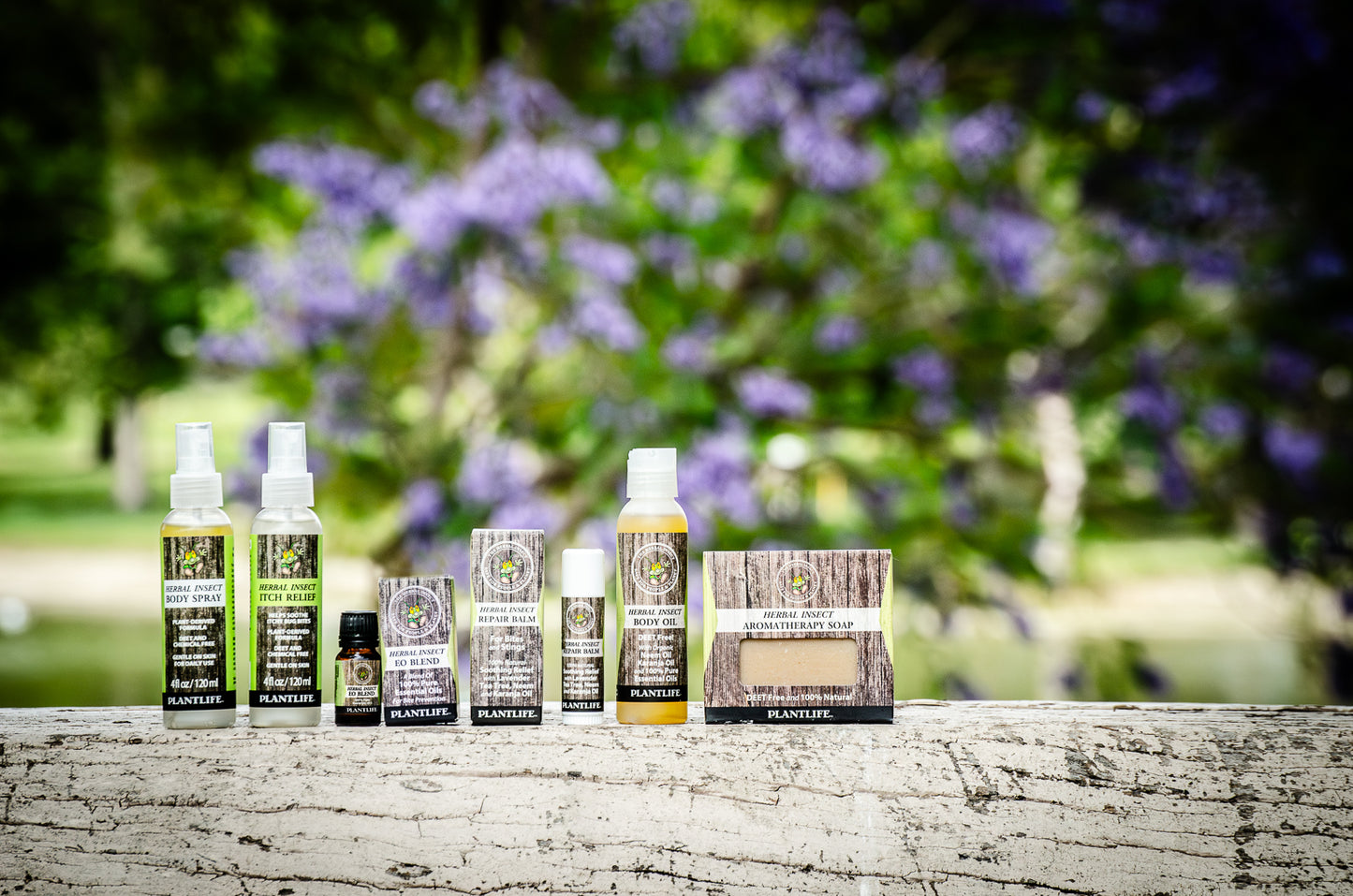 Plantlife Herbal Insect collection with body spray, itch relief, oil, balm, soap, and wax melts displayed outdoors in a garden setting