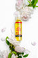 Bottle of Planteve body oil surrounded by white flowers on a white background