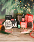 Collection of Christmas-themed products including bottles, a bag labeled 'Bag of Coal', and a gift box on a wooden surface with festive decorations.