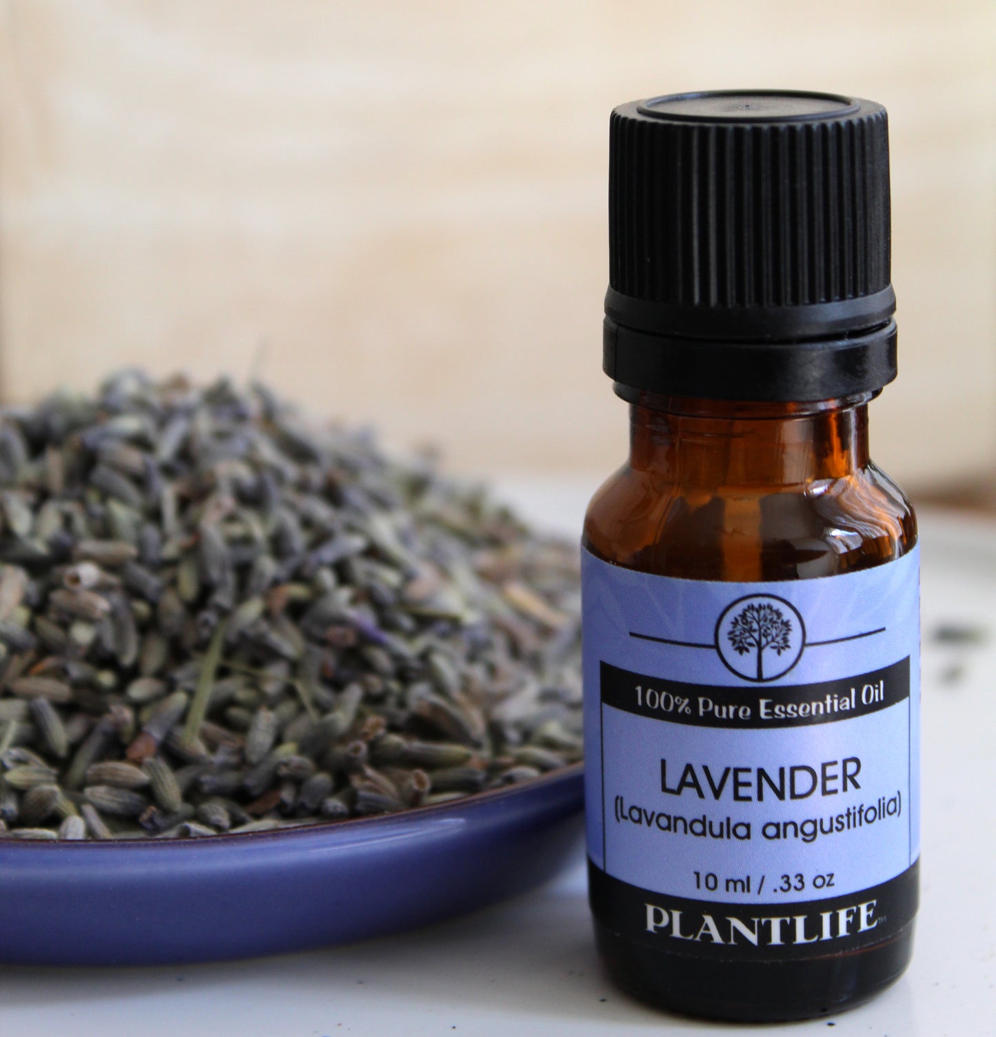 Bottle of Plantlife lavender essential oil with dried lavender flowers on a wooden surface