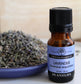 Bottle of Plantlife lavender essential oil with dried lavender flowers on a wooden surface