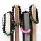 Three beaded bracelets on wooden blocks with a white background