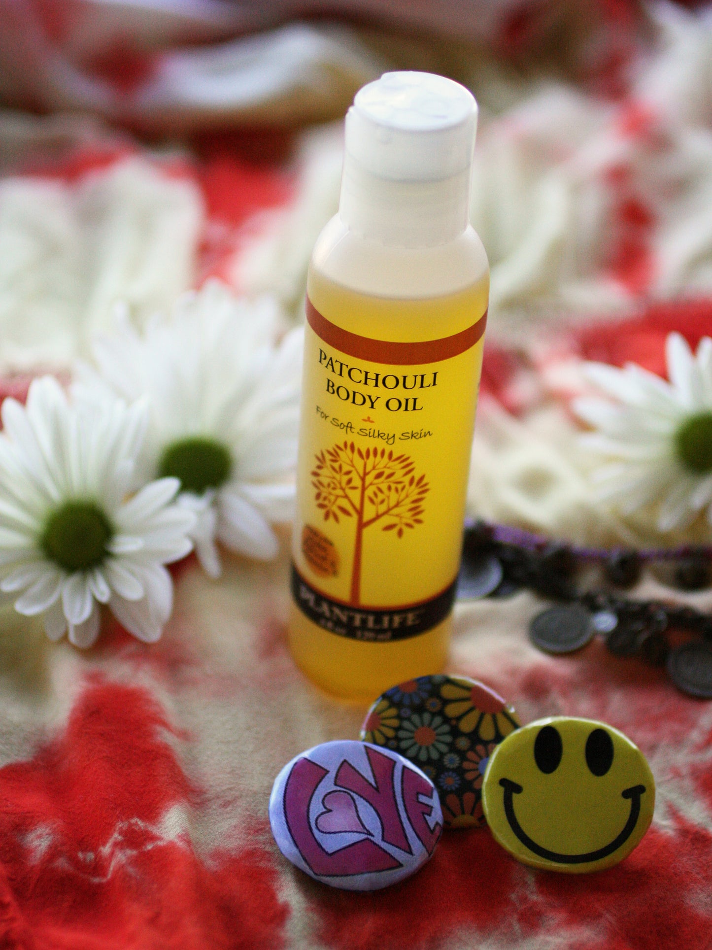 Patchouli body oil bottle with decorative buttons and flowers on a patterned fabric background