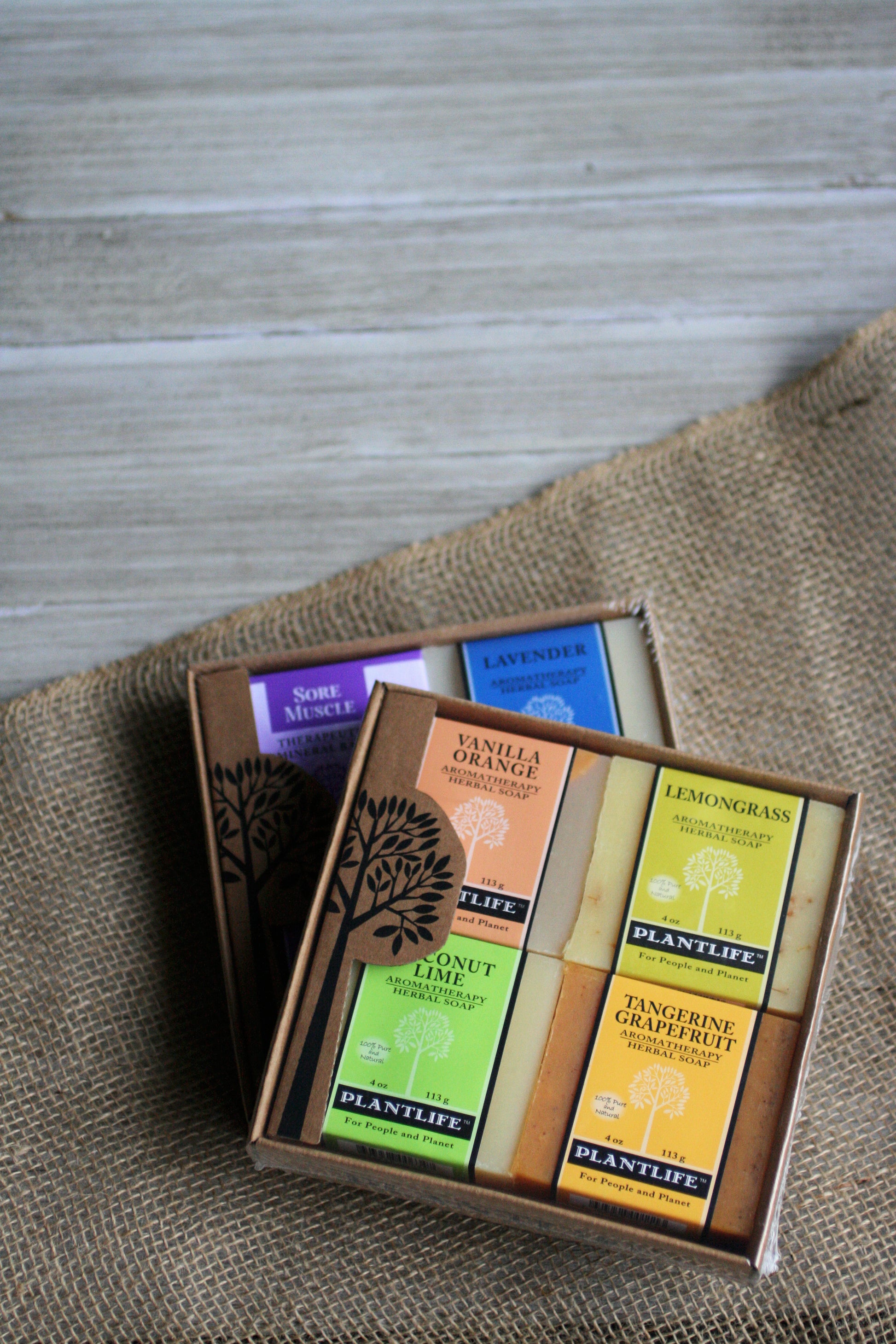 Box of Plantlife soap bars with various scents on a textured surface