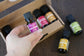 Hand holding a bottle of grapeseed oil with other essential oil bottles in the background.
