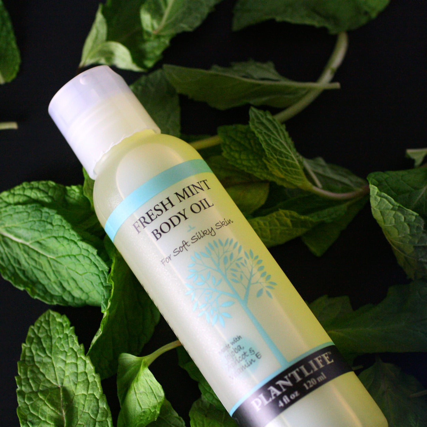 Plantlife Fresh Mint Body Oil bottle on a background of green leaves