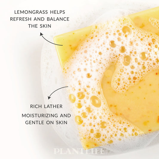 Close-up of a yellow Plantlife Lemongrass Soap bar resting in bubbly water. Text highlights “Lemongrass helps refresh and balance the skin” and “Rich lather, moisturizing and gentle on skin.” Handcrafted soap made with pure lemongrass essential oil for a bright, clean, and uplifting wash.