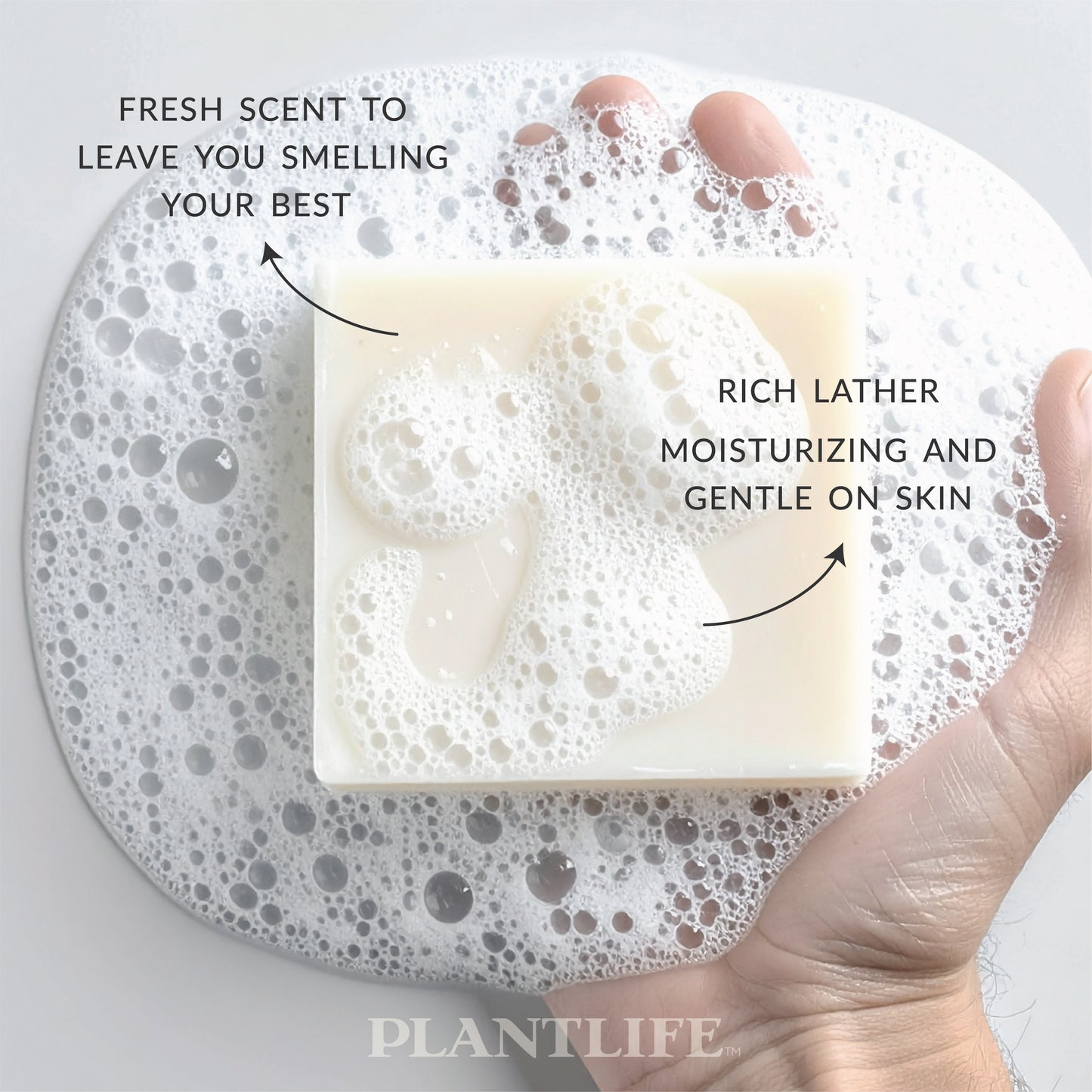 Bar of soap with bubbles on a gray plate, labeled for freshness and moisturizing properties.