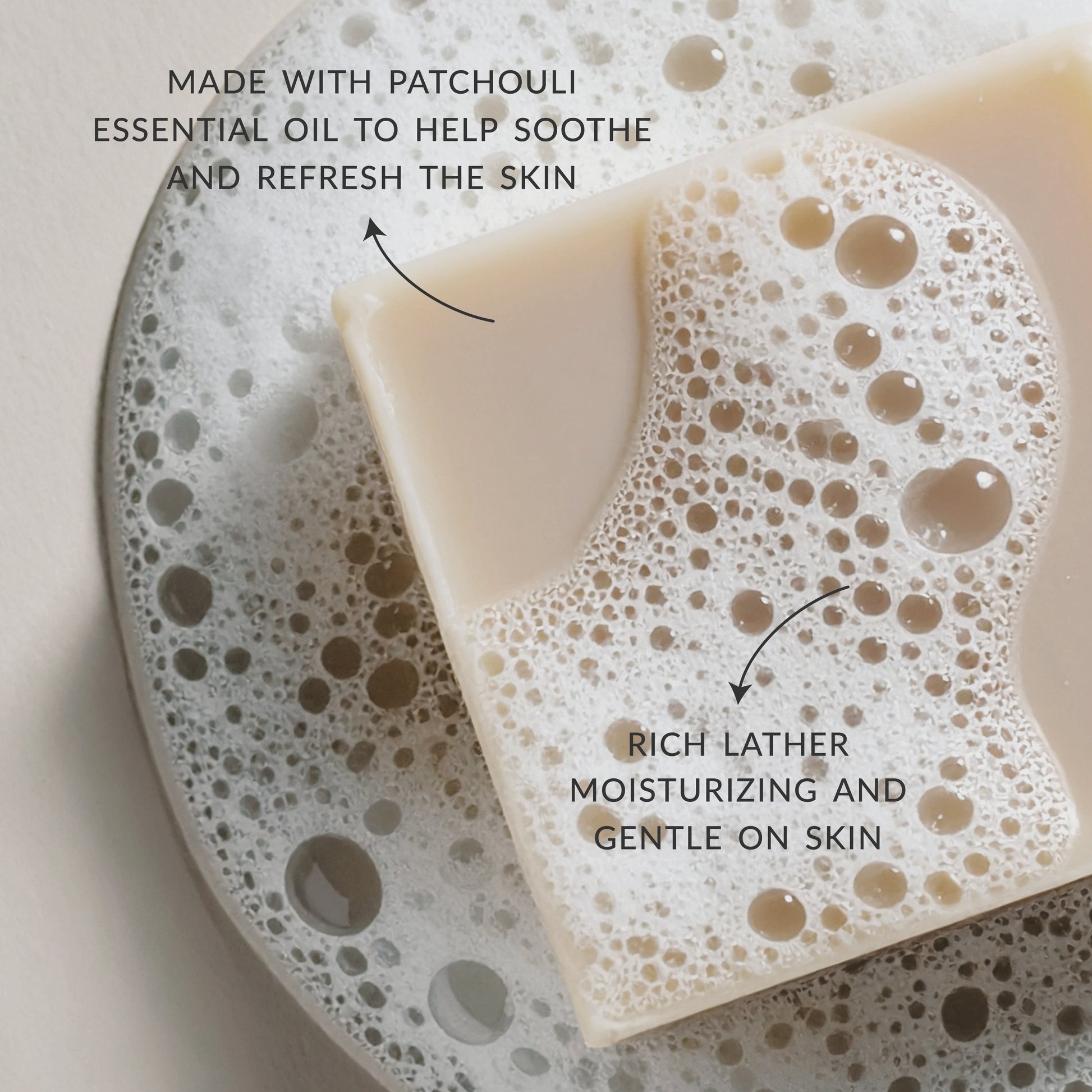 Close-up of a creamy beige Plantlife soap bar resting in foamy water. Text on the image highlights “Made with patchouli essential oil to help soothe and refresh the skin” and “Rich lather, moisturizing and gentle on skin.”