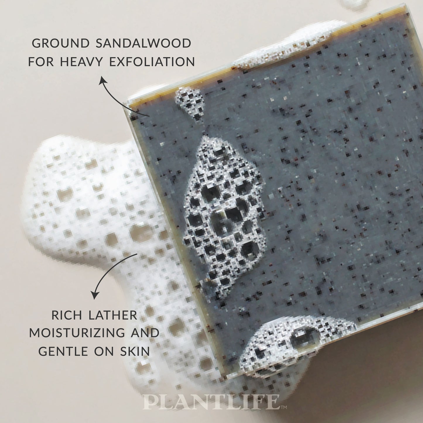 Close-up of a dark gray Plantlife soap bar with visible exfoliating particles resting in foamy water. Text on the image highlights “Ground sandalwood for heavy exfoliation” and “Rich lather, moisturizing and gentle on skin.”