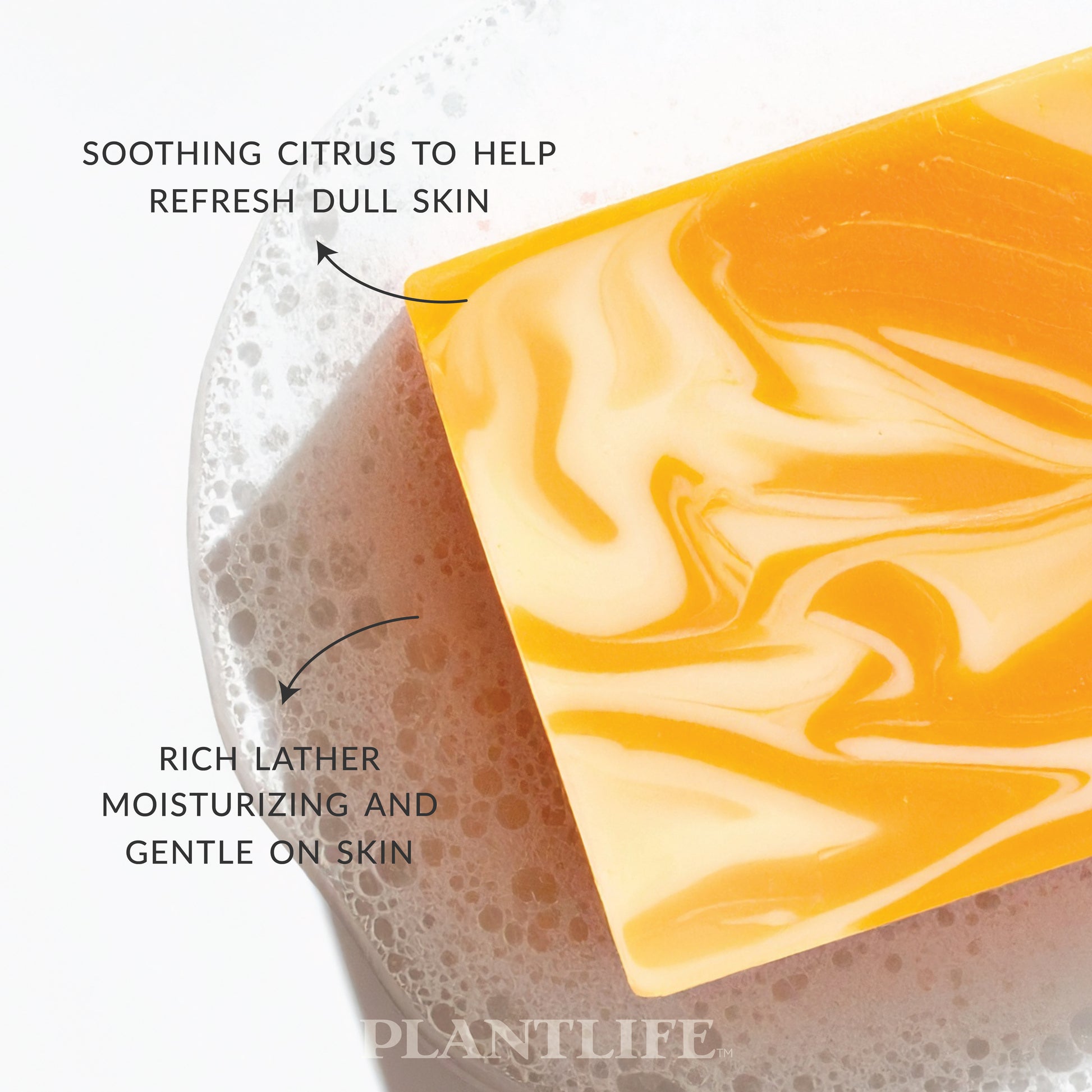 Plantlife Vanilla Orange Soap resting on foamy bubbles. Text reads “Soothing citrus to help refresh dull skin” and “Rich lather moisturizing and gentle on skin.” Bright orange and cream swirled bar made with essential oils for a naturally uplifting shower experience.